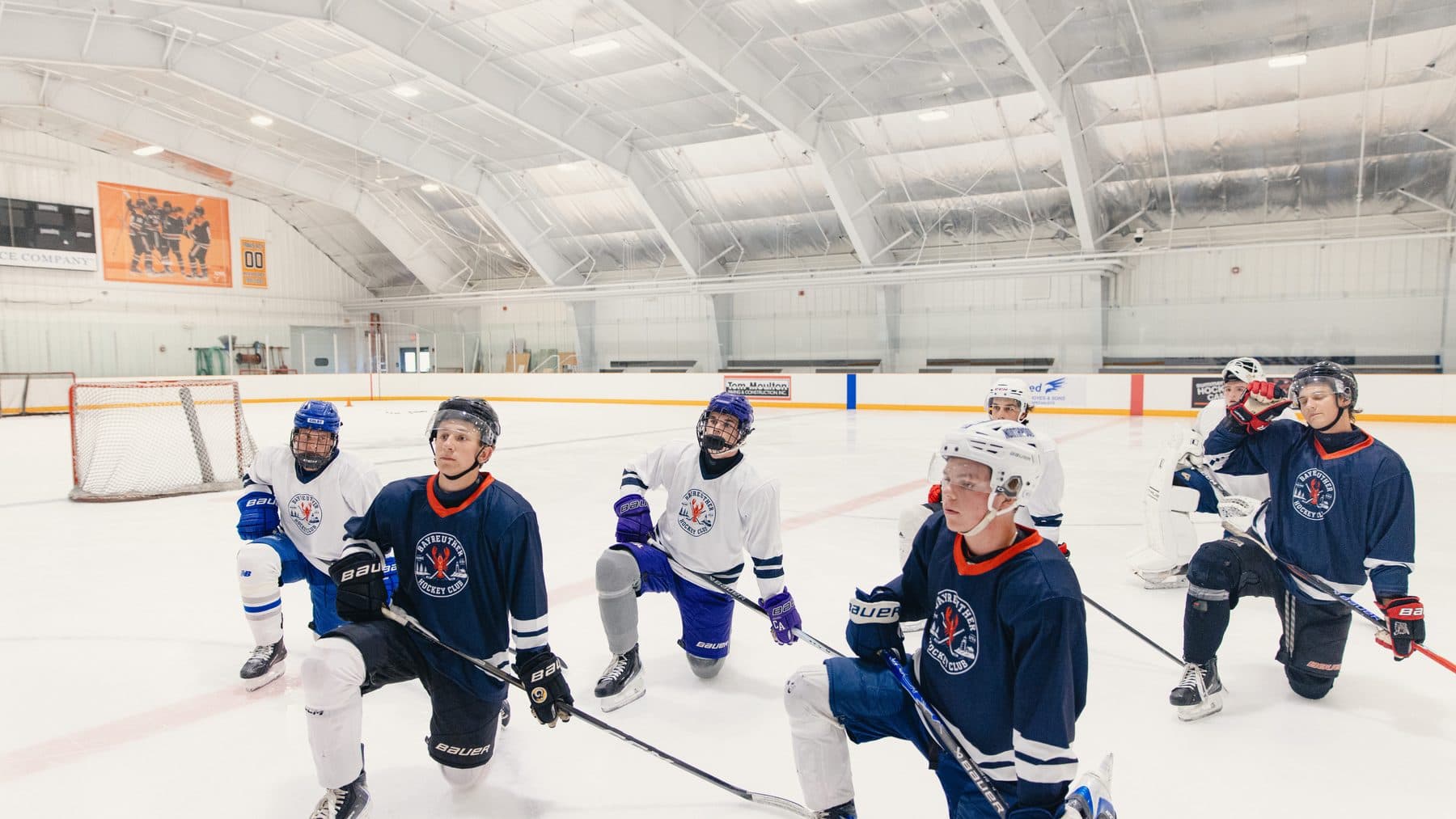 Players kneeling on the ice listening to Gavin Bayreuther at a BHC camp